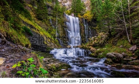Waterfall in the autumn forest. Autumn forest waterfall. Autumn waterfall in autumn forest. Waterfall landscape