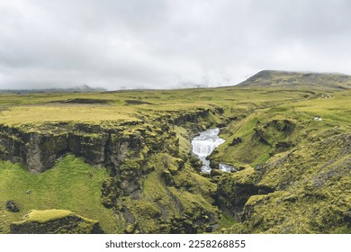 Waterfall in the beautiful landscape in Icelandic environment during cloudy, misty day