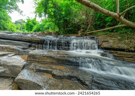 Waterfall called Tat Yai Waterfall with rock layer and green forest background in local area called Nam Nao District, Phetchabun, Thailand.