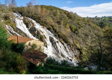 Brañas waterfall. It is a cascade of about 40 meters over a huge rock wall that has a water mill on its left side. Toques, A Coruña, Spain.