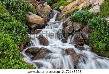 Waterfall from the creek flow over the stones. Forest creek water in waterfall stream
