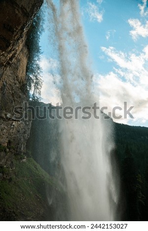Waterfall flow in the mountains on blue sky background.stream of water with drops and splashes.Rushing water falls on large stones.