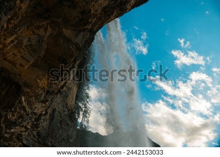 Waterfall flow in the mountains on blue sky background.stream of water with drops and splashes.Rushing water falls 