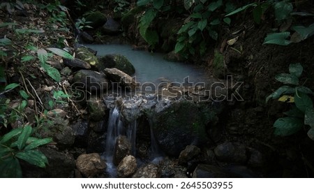 Waterfall flow in a small river in the dark forest. Tropical forest background with waterfall in a river flow in the middle of the forest. Dark tropical forest background like a dream.