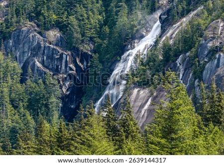 Waterfall flowing amid lush forest and rocky terrain in Squamish, BC, Canada.