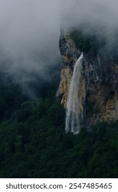 A waterfall flowing down a mountainside surrounded by mist