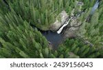 A waterfall flows in the middle of the forest in Puolanka