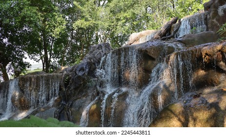 The waterfall has trees and rocks.