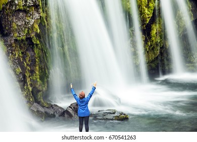  Waterfall Kirkjoufellfoss. Elderly Woman -  Traveler Enthusiastically Raised Her Hands. Summer In Iceland. Concept Of Exotic And Extreme Tourism 