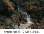 Waterfall with ladder in canyon, sucha bela. Icefall in the gorge of Slovak paradise national park. Spring hiking trail with ice structures and steel climing ladder. Adventure travel in Slovakia