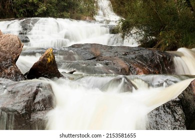 Waterfall With A Large Volume Of Water That Flows Through Several Rocks.