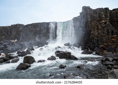 Öxarárfoss waterfall in late winter, flowing from the river Öxará over black basalt rocks into the Almannagjá gorge, Þingvellir National Park, Golden Circle Route, Iceland
