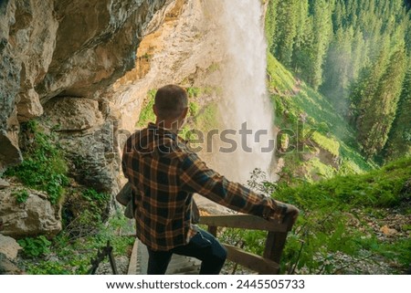 Waterfall and man and stairs to the waterfall.flow of a waterfall in the mountains. Rushing water falls on large stones.