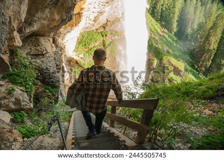Waterfall and man and stairs to the waterfall.flow of a waterfall in the mountains. Rushing water falls on large stones.Water boils and pours over large boulders and stones.