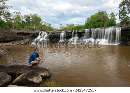 Waterfall with man,mature man in outdoor leisure activity alone. Male people in meditation with waterfall background.Ubon ratchathani province,Thailand,ASIA