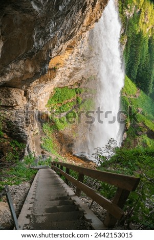 Waterfall and man.Waterfall in the mountains.stormy stream of water with drops and splashes. Powerful stream of a waterfall from a high cliff.