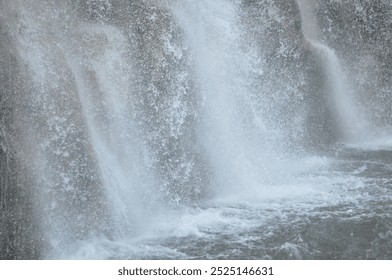 A waterfall with a misty, foggy appearance. The water is falling in a continuous stream, creating a sense of movement and energy. The misty atmosphere adds a sense of mystery - Powered by Shutterstock