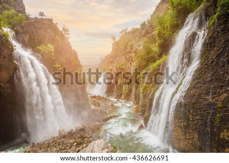 waterfall in mountain forest under great sky.