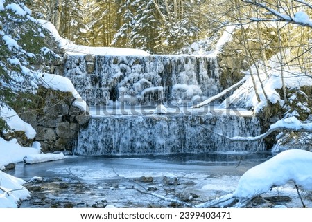 Waterfall on the hiking trail to Vilsalpsee in the sunshine. Frozen cascades near Tannheim in the Austrian Alps.
