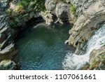 Waterfall pouring into a swimming hole.