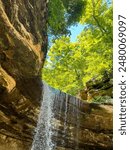 Waterfall in a Sandstone Canyon with Beautiful Rock Formations. Green leafy trees surround the scene. Located within Starved Rock State Park in LaSalle County, Illinois, USA.