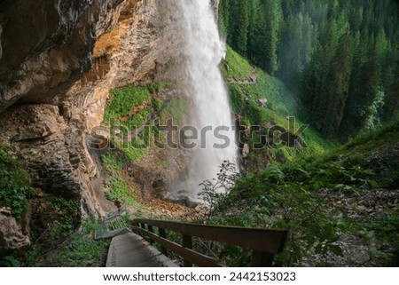 Waterfall and stairs to the waterfall. Rushing water falls on large stones.Water boils and pours over large boulders and stones.stream of water with drops and splashes