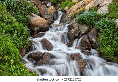 Waterfall from the stream flows over the stones. Waterfall stream on rocks. Cold creek flow on waterfall rocks. Waterfall rocks
