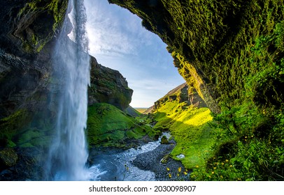 Waterfall streams in the green mossy mountain arched cave
