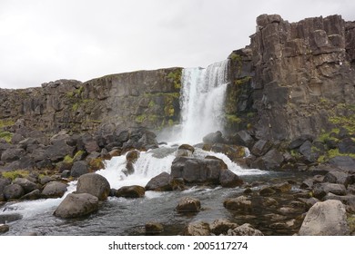 Öxarárfoss waterfall in Thingvellir National Park, Iceland, set against an overcast sky