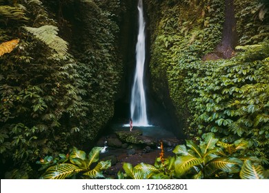 Waterfall in tropical jungle and alone woman in bikini. Leke Leke waterfall in Bali, Indonesia