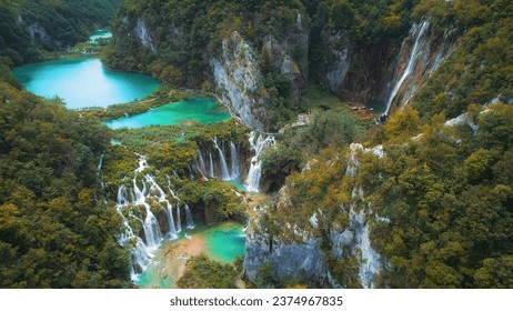 Waterfalls in the autumn forest flowing into lakes. Tourists visit famous Plitvice park in Croatia. Mountain streams with clear water.