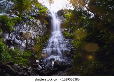 A Waterfalls With Beautiful Sunrays Reflecting On The Camera Lense. It Increases The Beauty Of The Picture. 