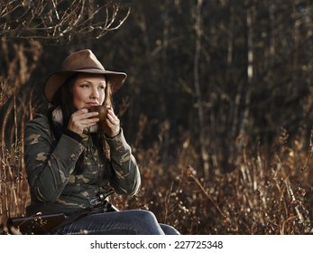 Waterfowl hunting, the female hunter having a coffee break, autumnal bushes on background
