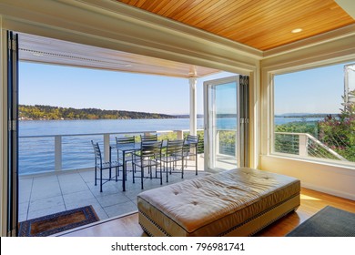 Waterfront home interior - a sliding glass wall opens to Large covered deck with comfortable outdoor dining space and stunning views of Lake Washington and Mt. Rainier. Northwest, USA