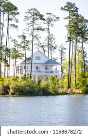 Waterfront Home On Stilts Surrounded By Tall Pine Trees.