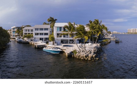Waterfront homes with private docks in Miami, Florida. Row of houses facade with balconies near the waterways against the dark sky background.