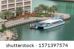 Waterfront promenade with water taxi in Dubai Marina aerial timelapse. Boats and yachts floating on canal. Dubai, United Arab Emirates