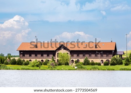 Waterfront Rustic Barn House Overlooking Calm Lake in Green Countryside Landscape, Summer Panorama