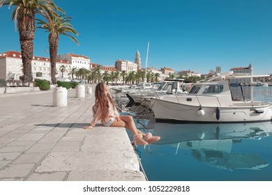 Waterfront Of Split, Croatia. Young Female Traveler With Pink Backpack Enjoying The Seafront. Woman Looking At View Diocletian Palace On Famous Travel Destination.