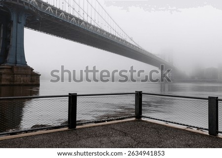 Waterfront view of the Manhattan Bridge covered by dense fog