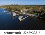 Waterfront villas with private docks at Navarre, Florida. Aerial view of residences with fence walls and some docks with roofs and boat lifts.