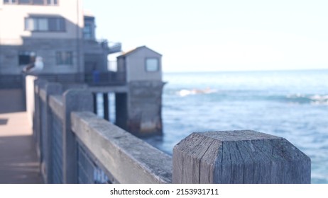 Waterfront wooden boardwalk in Monterey, California USA. Beachfront promenade on piles, pillars or pylons by ocean sea water and bay aquarium on Cannery Row street. Tourist vacations waterside resort.