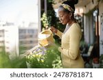 Beautiful woman watering plants on the balcony
