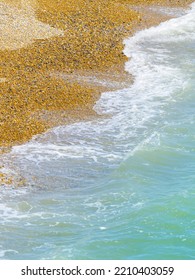 Waterline On Brighton Beach Close-up Sea Washing In On Orange Coloured Pebbles In Vertical Composition.