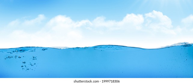 Waterline with sea underwater and blue sunny sky with clouds and sun