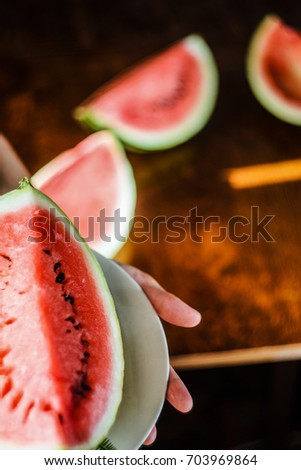 Watermelon background. Plate with a large slice of watermelon against a background of a blurry table with slices of watermelon
