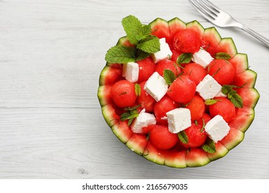 Watermelon Feta salad with watermelon scoops,feta cheese and mint leaves in watermelon basket with white wood table background.Fresh and healthy Italian summer salad.Copy space
				
				