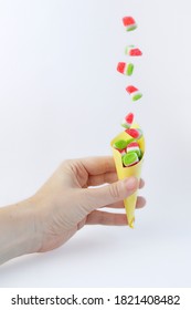 Watermelon Jelly Beans Falling Into A Paper Cone Held In One Hand