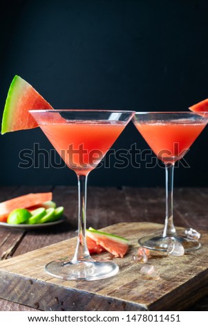 Watermelon Margarita cocktail in two Martini glasses. Ingredients: watermelon, Agave syrup, Tequila, fresh lime juice and ice. Wooden table and wooden background. Beverage photography