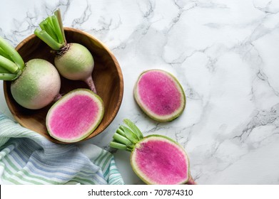 Watermelon red radish (chinese daikon) on marble table. Top view. Unusual healthy colorful vegetable. 